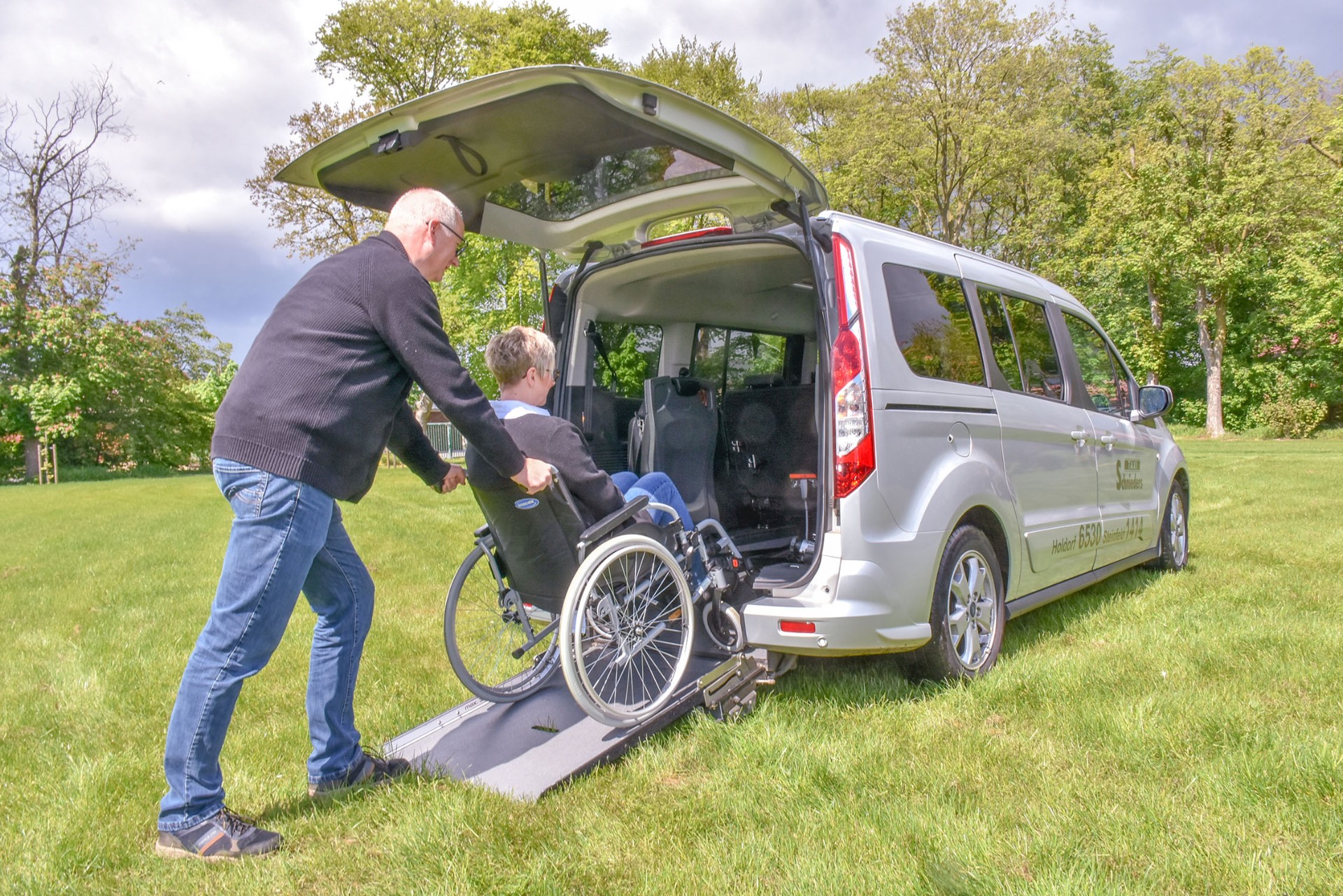 Rollstuhlfahrerin wird über die Heckrampe eingeladen